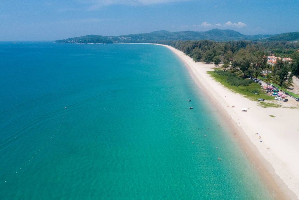 Golden hues on quiet Phuket Surin with tall palms and gentle waves