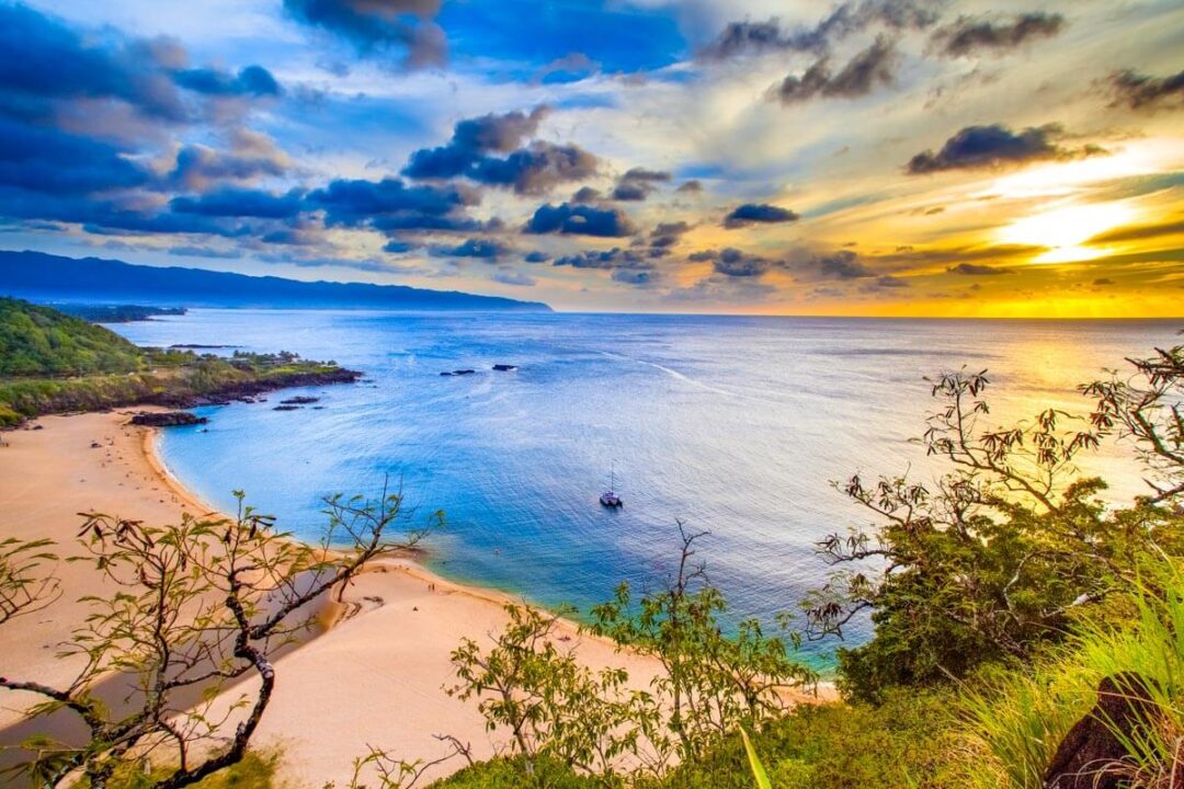 Golden light on empty Lombok beach with soft tide and distant palm trees